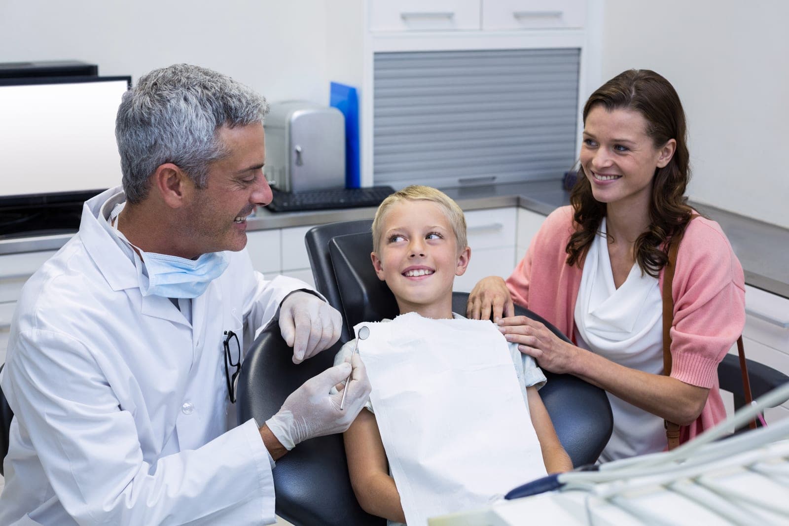 A friendly dentist examining a young patient alongside their parent at Chapel House Dentistry